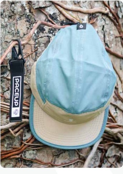 Gorra Paceup celeste sobre un tronco con llavero de la marca