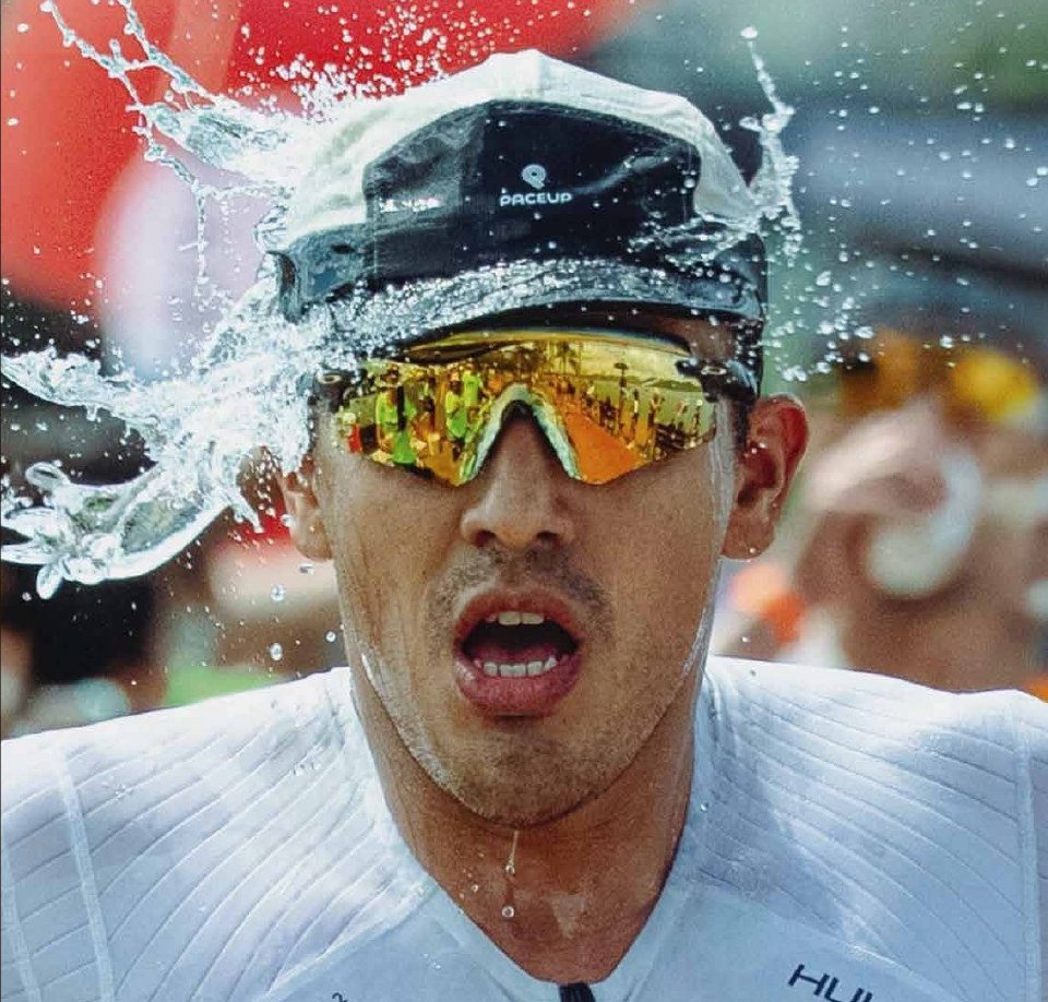 Corredor con gorra Paceup recibiendo agua en plena carrera